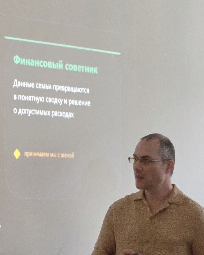 Стас Ганиев выступает с докладом, за ним слайд презентации