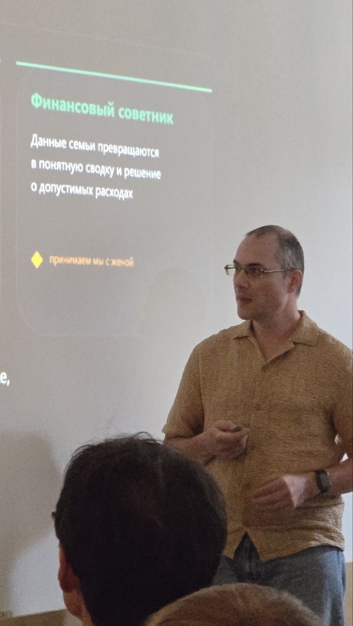 Стас Ганиев выступает с докладом, за ним слайд презентации